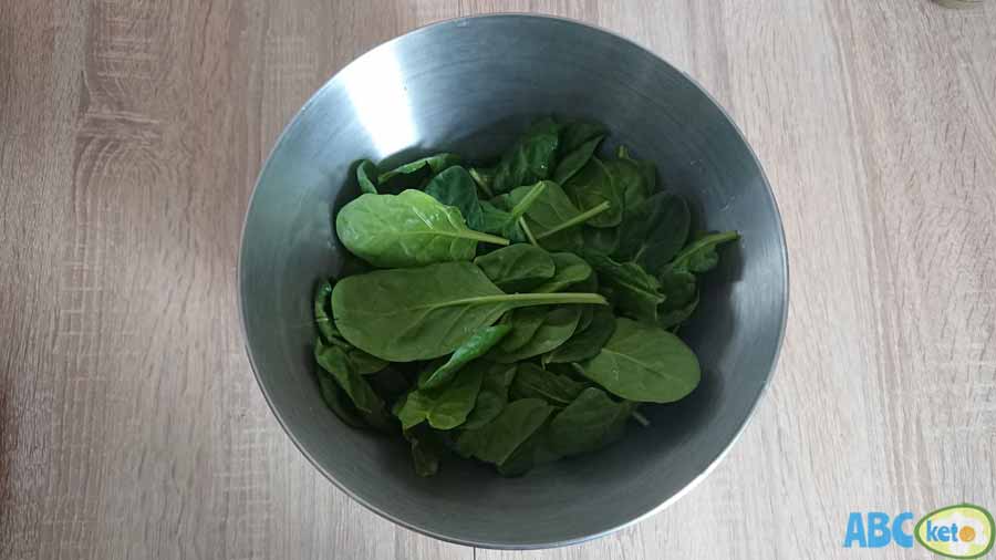 Keto salmon salad instructions, putting spinach leaves into a bowl